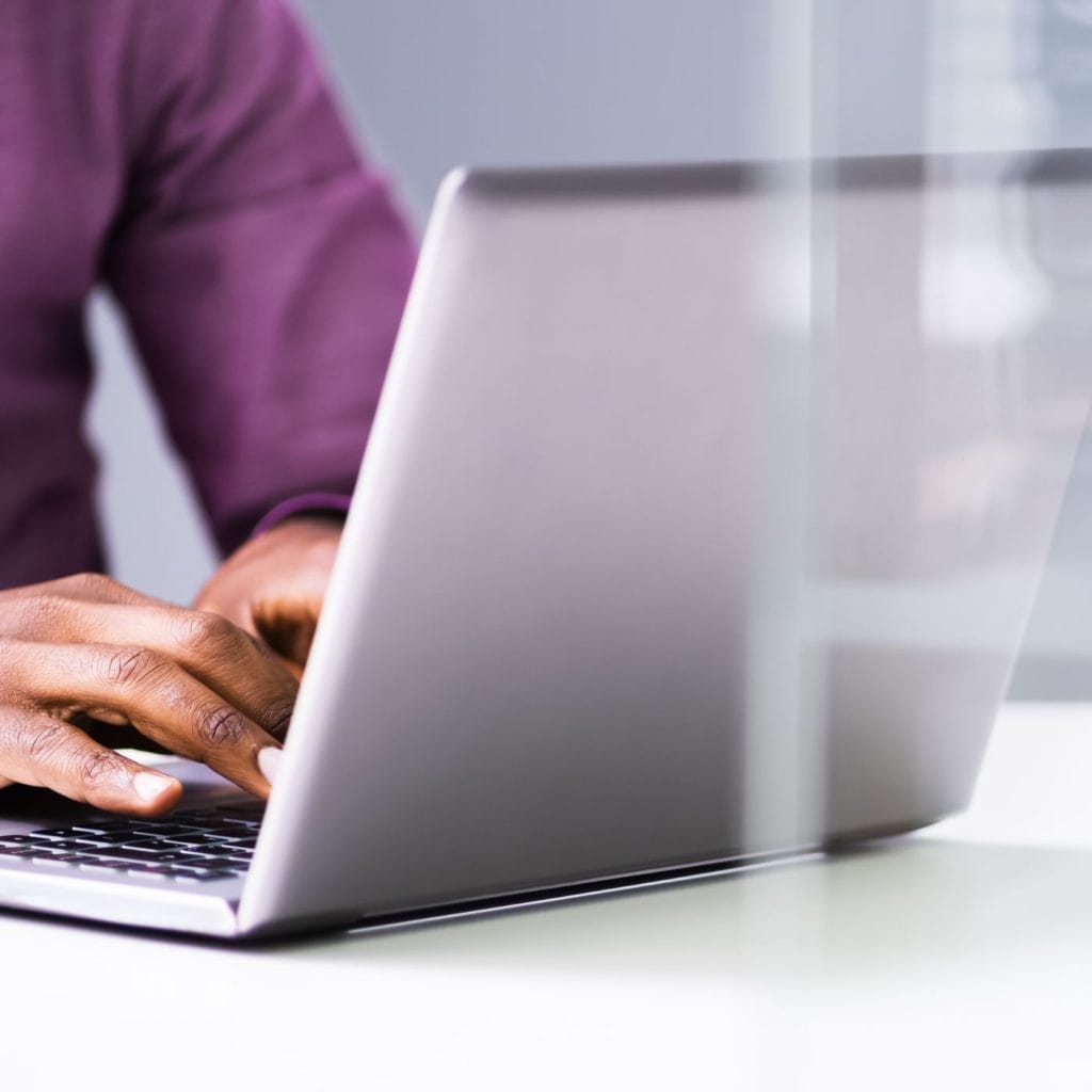 A person typing on a laptop utilizing client references